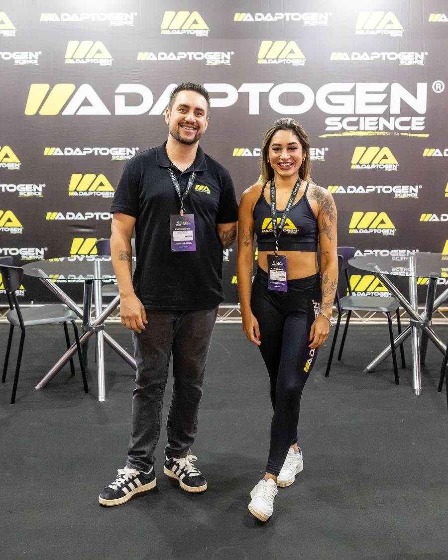 Casal de expositores sorrindo em um estande compacto de suplementos